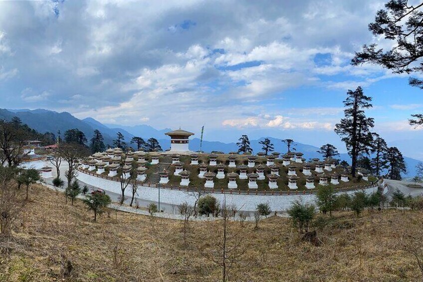 A pagoda surrounded by prayer flags on a hillside. 3