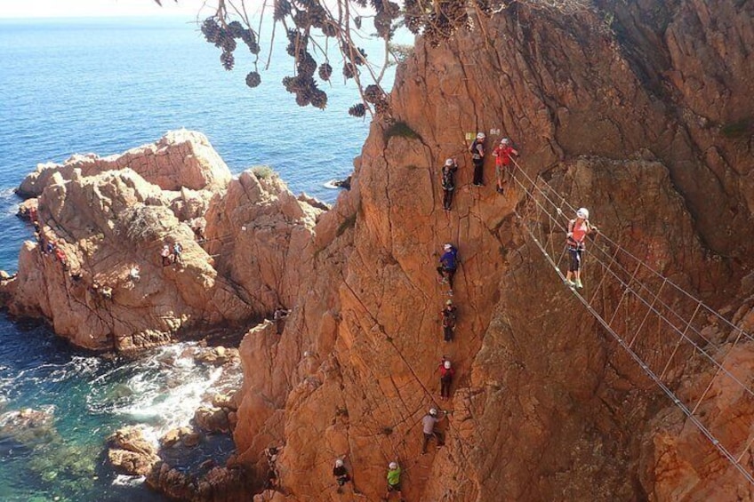 Eine Gruppe von Menschen klettert an einer felsigen Klippe entlang eines Gewässers. 2