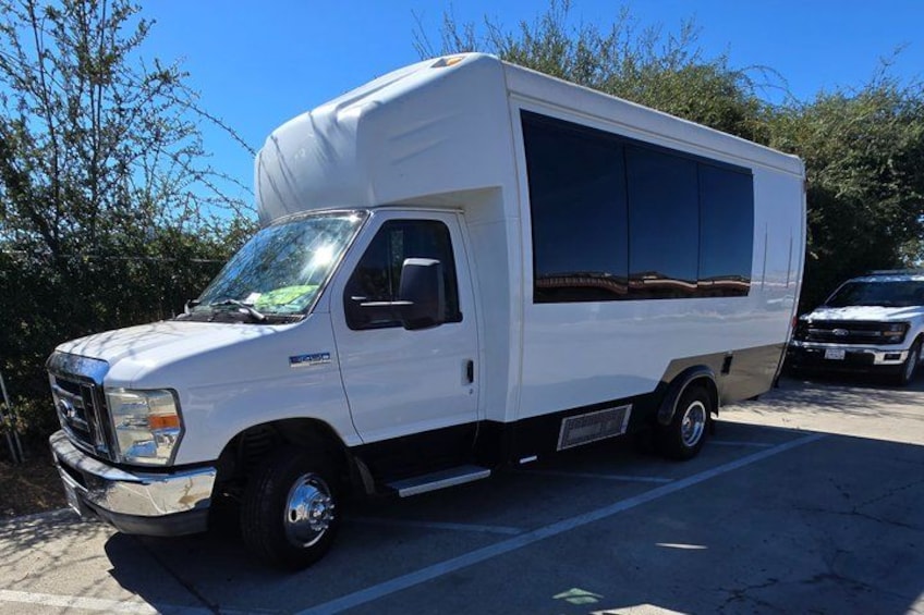 A white recreational vehicle parked in a lot with trees in the background. 4