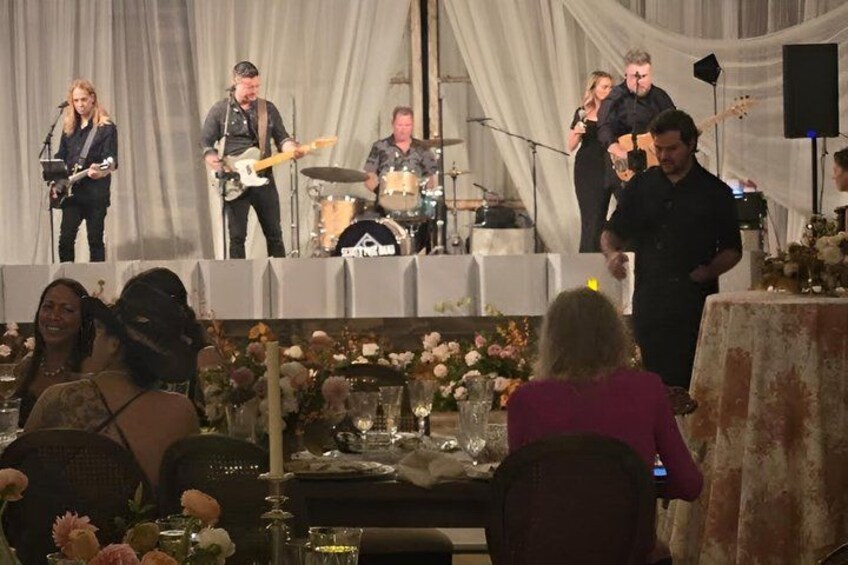 A band performing on stage with a seated audience at a formal event. 3