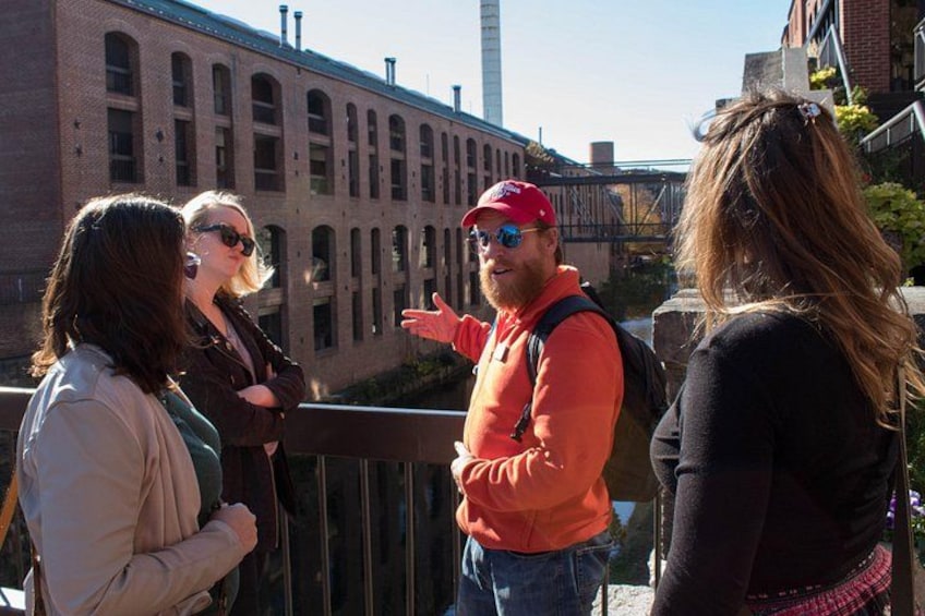 A group of people standing on a bridge with a brick building in the background. 2