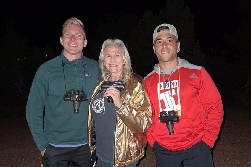 Three people outdoors at night, each holding a camera. 2