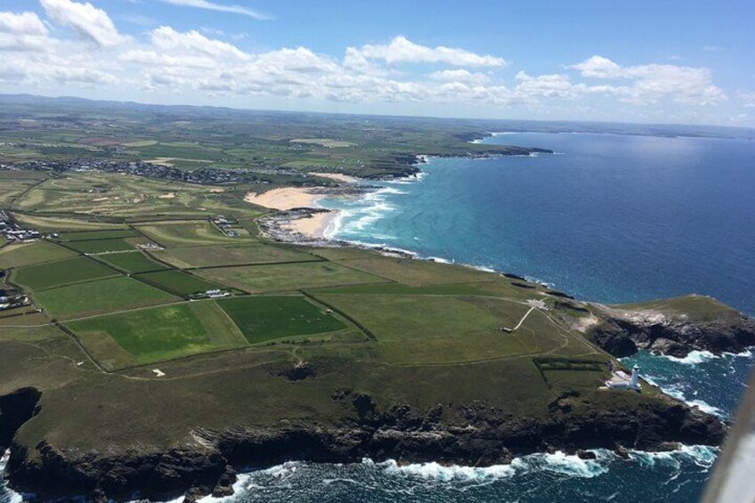 A coastal landscape with fields, a beach, and rocky cliffs. 1