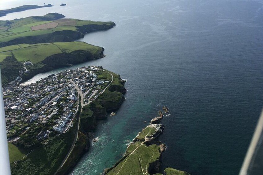 A coastal town with a winding road along the cliffs, a small harbor, and a distant island. 5