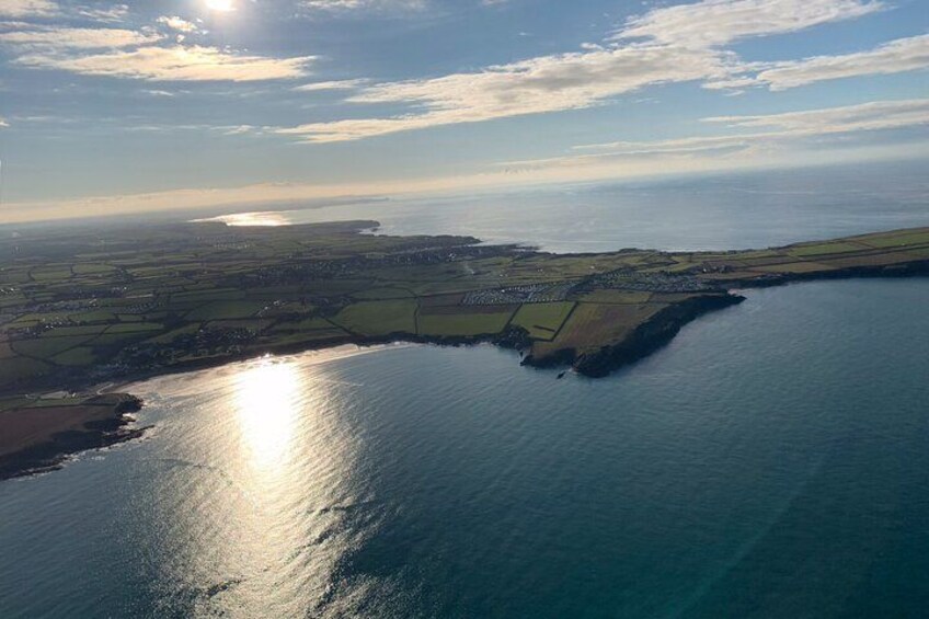 A coastal landscape with a body of water, land with fields, and a distant shoreline. 4