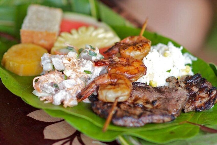 A plate of grilled meats, shrimp, and rice on a banana leaf. 5