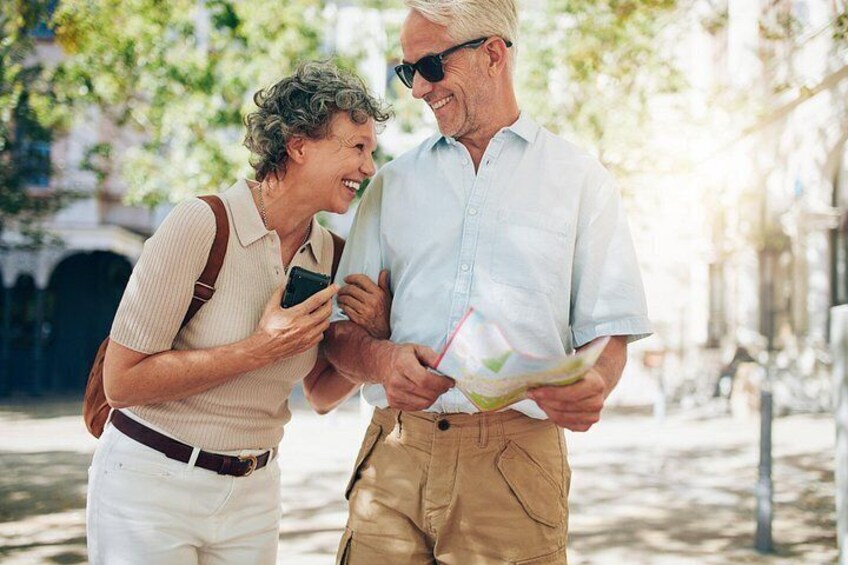 Two people examining a map outdoors, with trees and buildings in the background. 3
