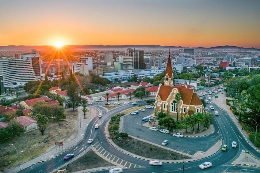A cityscape with a prominent church, a roundabout, and a sunset. 1