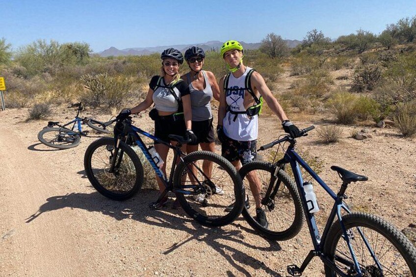 Three people with bicycles in a desert landscape. 2