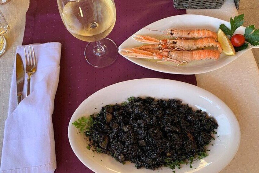 A plate of cooked seafood, a glass of white wine, and a plate of greens. 5