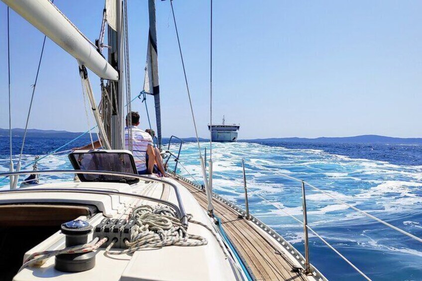 A sailboat on the ocean with a person steering and another person sitting. 4
