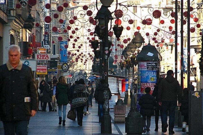 A busy urban street with people walking, street lamps, and signs advertising destinations like Dubai and Istanbul. 2