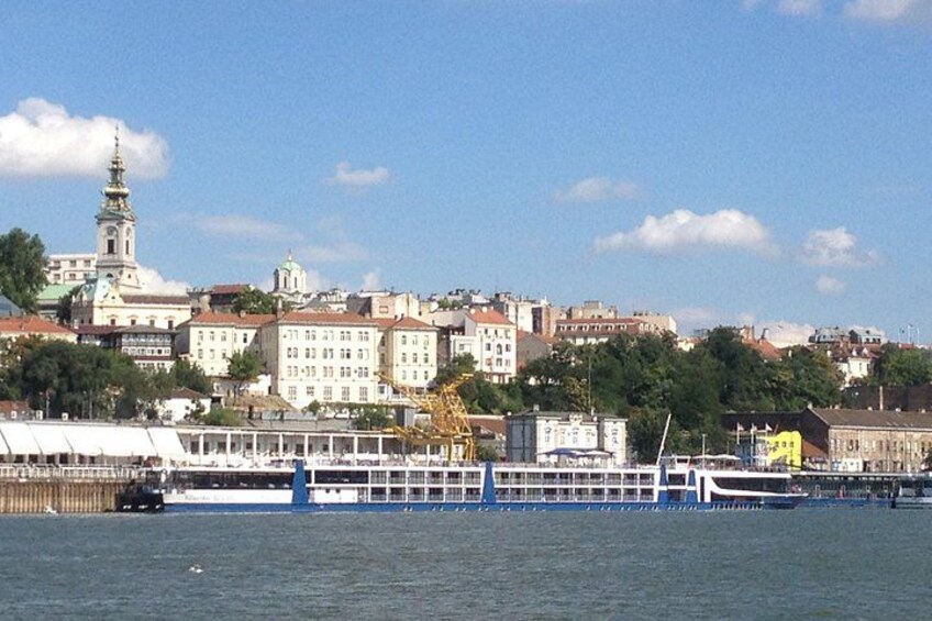 A river with a boat, buildings, and a tower in the background. 3