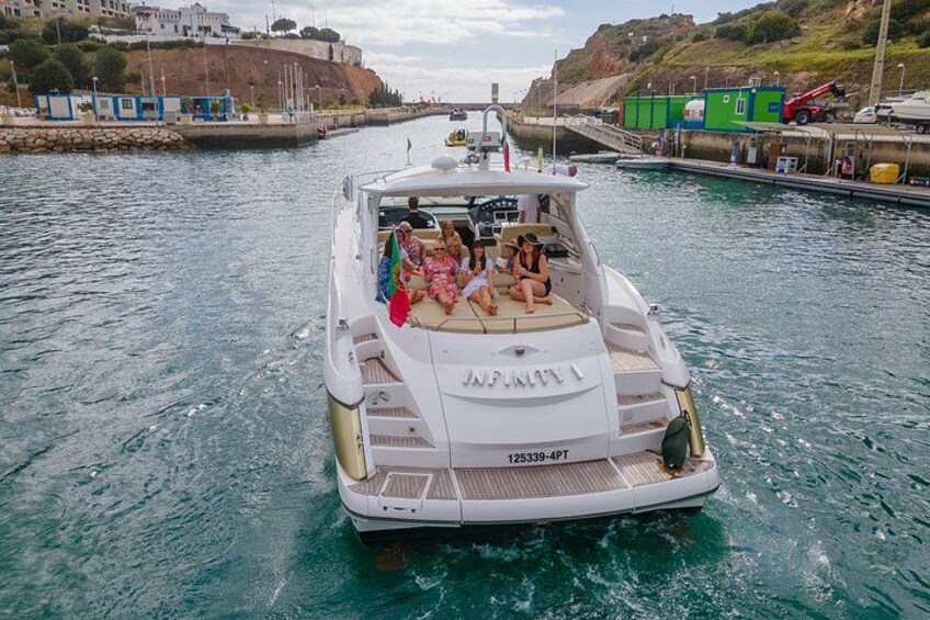 A white speedboat with the number 125339-4PT on the bow, moving through a narrow waterway with a dock on the left and a green building on the right. 3