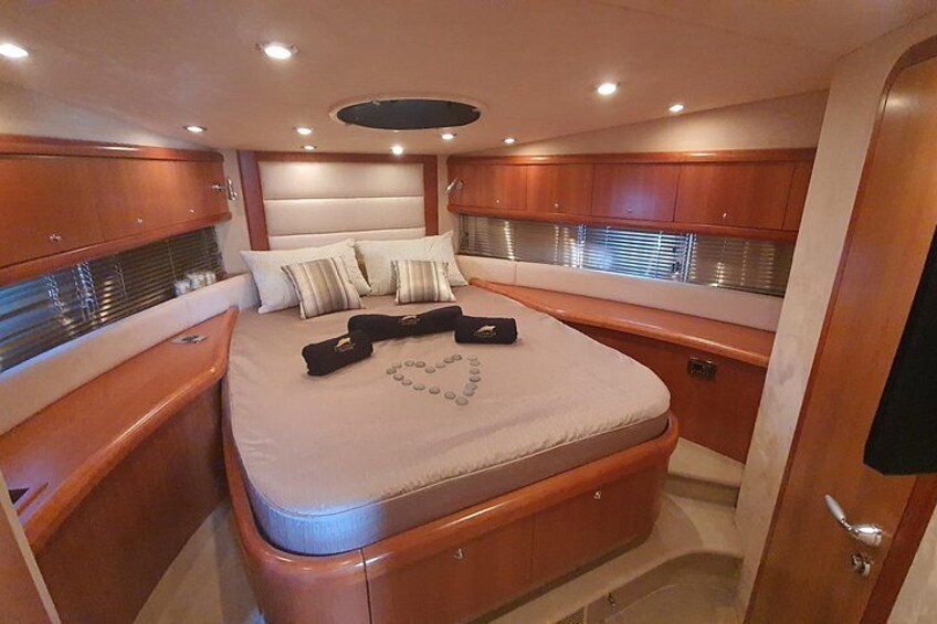 A compact, well-lit cabin with a bed, wooden cabinets, and a small seating area. 5