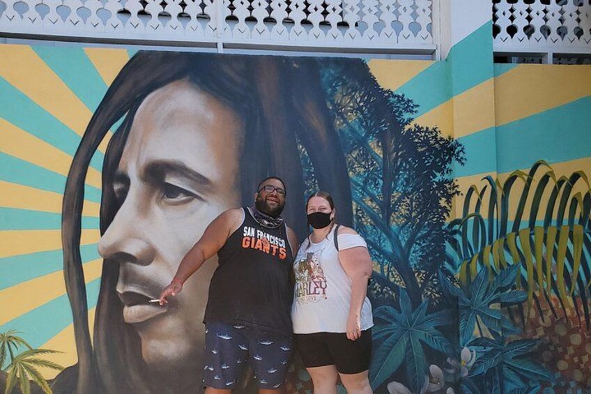 A mural with a large portrait and tropical foliage. 2