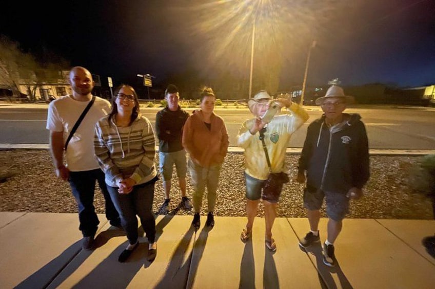 A group of people standing on a sidewalk at night. 3