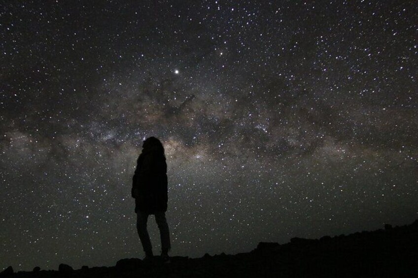Una persona de pie en una colina bajo un cielo estrellado. 2