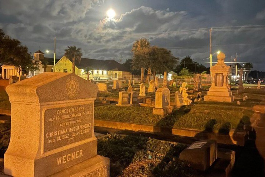 A cemetery at night with tombstones and a cloudy sky. 2