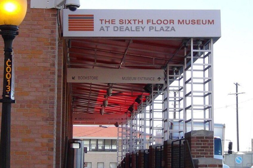 Un panneau indiquant l’emplacement du Sixth Floor Museum, situé sur Dealey Plaza, avec des indications pour se rendre à la librairie et à l’entrée du musée. 2