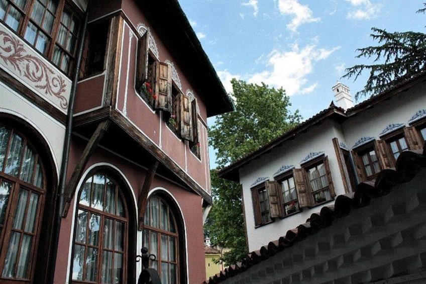Un bâtiment traditionnel doté de fenêtres en arc de cercle et d’un balcon avec des volets en bois. 1