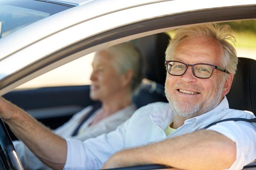 A person driving a car with another person seated in the back. 3