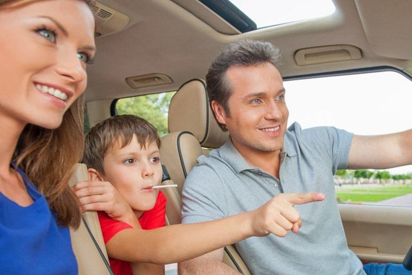 A family inside a car with a man pointing out the window. 5