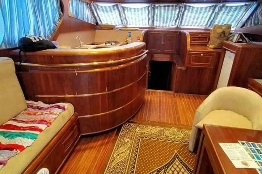 A compact, wooden interior with a curved bench, a small sink, and a patterned rug. 3