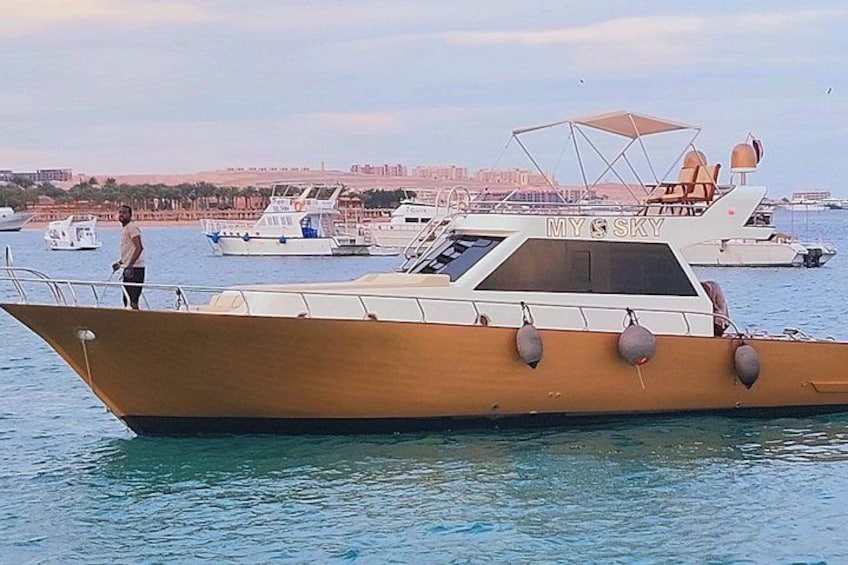 Un barco de madera llamado 'MY SKY' amarrado en un puerto deportivo, con otros barcos al fondo. 4