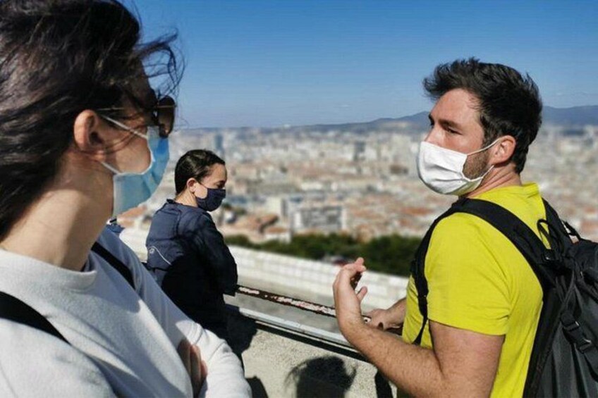 Una persona con camisa amarilla de pie en un balcón, con un paisaje urbano de fondo. 5