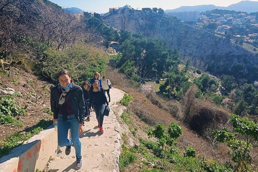 Un grupo de personas caminando por un sendero de tierra rodeado de vegetación y colinas. 2
