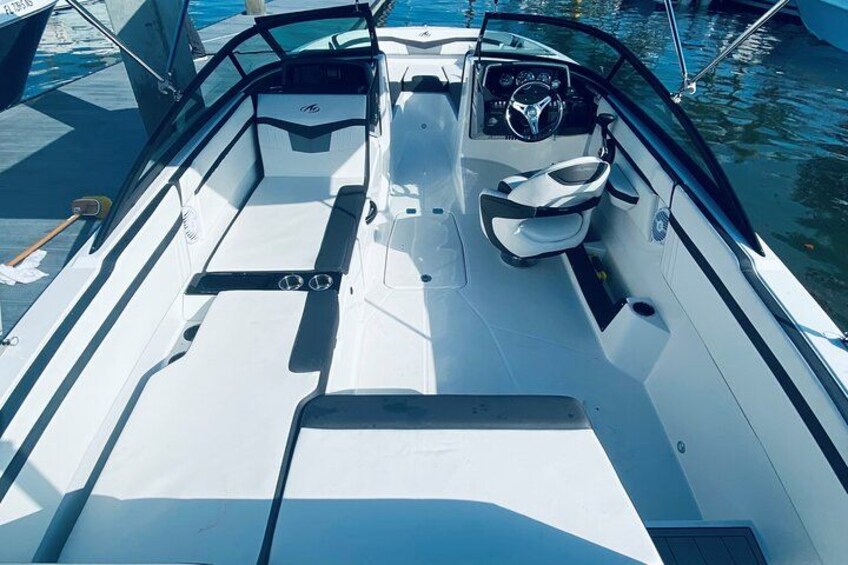 A boat's interior with a steering wheel, seating, and a control panel. 2