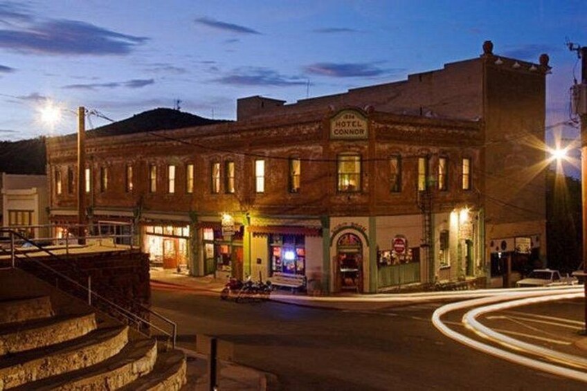 A historic building with a sign that reads 'Hotel Connor,' surrounded by a street with a light trail indicating motion. 1