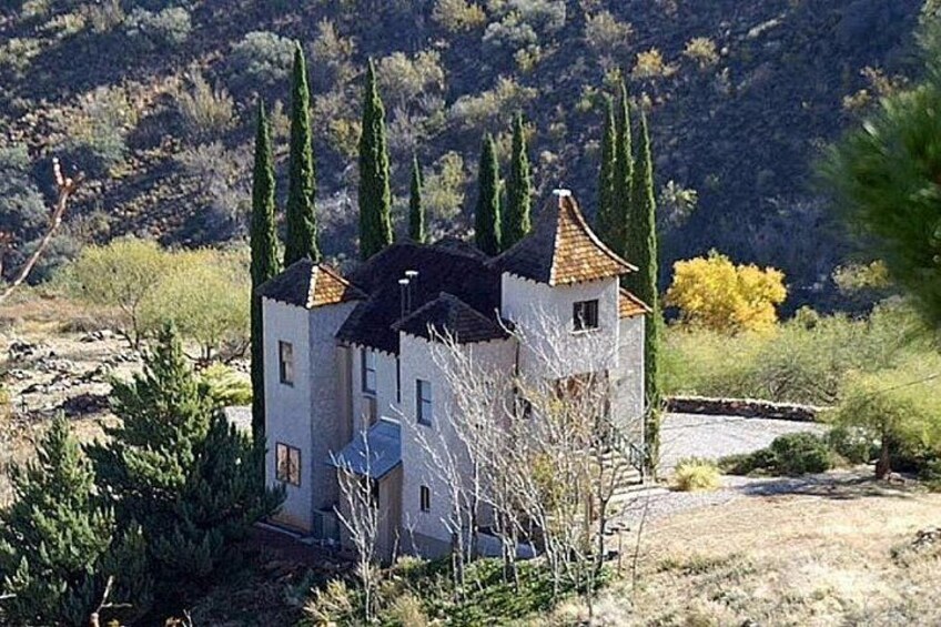 A white building with a tiled roof, surrounded by cypress trees and a hilly landscape. 3