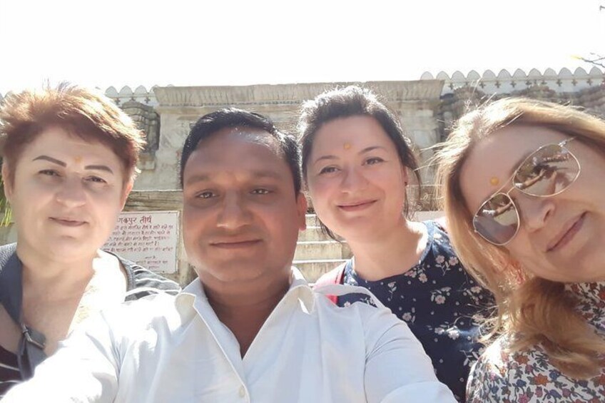Four people posing in front of a historical building with inscriptions. 2
