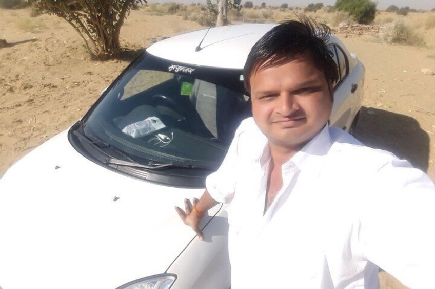 A person standing next to a white car in a desert landscape. 3