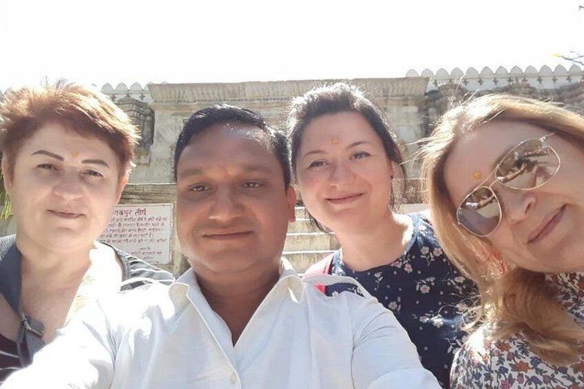 Four people taking a selfie in front of a historical building with inscriptions. 2