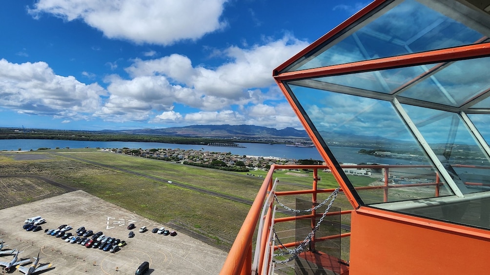 A glass-enclosed observation tower with a view of a lake, a town, and mountains in the distance. 4