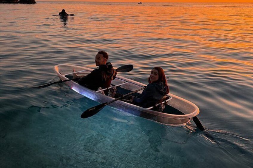 Two people in a kayak on calm water during sunset. 1