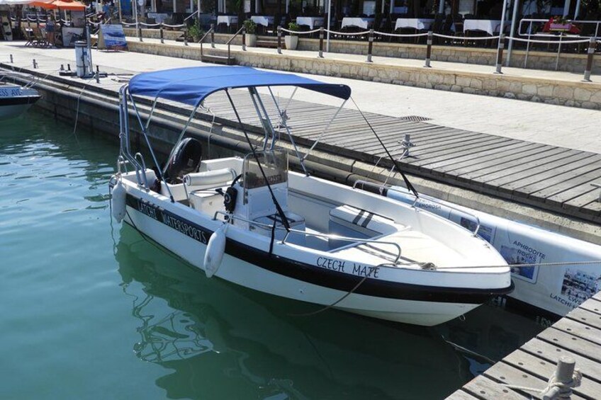 A white boat named 'Czech Mate' docked at a marina with a blue canopy. 1
