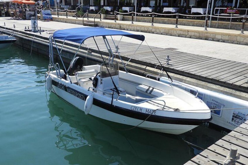 A boat named 'Czech Mate' docked at a marina with a blue canopy. 1