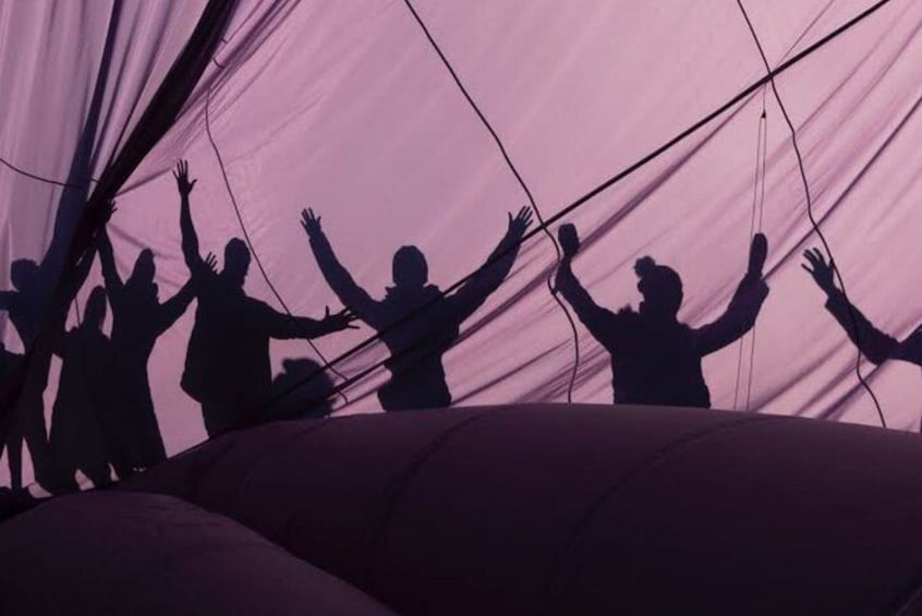 Silhouettes of people with raised hands inside a tent. 2