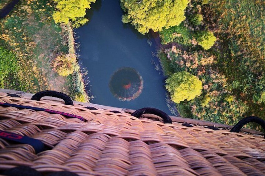 A river surrounded by trees, a wicker basket, and a person in the distance. 4