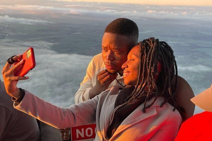 A person taking a selfie with another individual in the background. 3