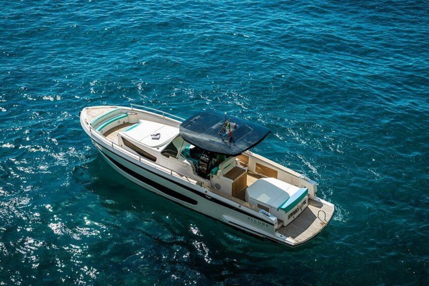 A white motorboat with a covered deck and a cabin, floating on clear blue water. 4
