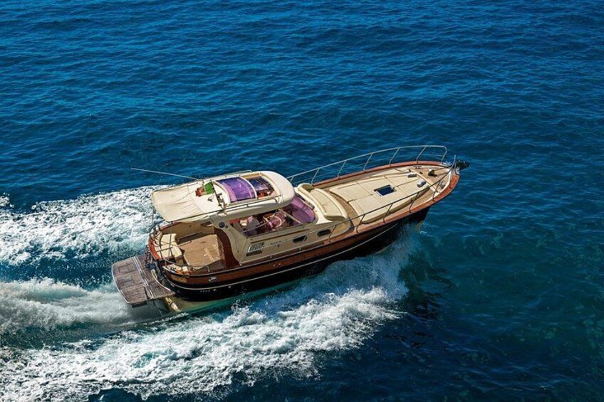 A speedboat with a cabin and a canopy, moving through clear blue water. 2