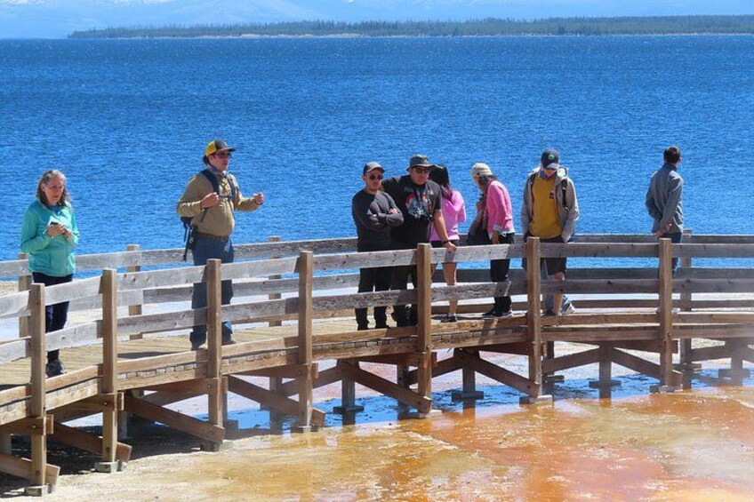 A group of people on a wooden dock by a large body of water. 5