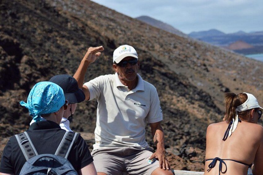 A group of people sitting on a rocky terrain with a mountainous landscape in the background. 5