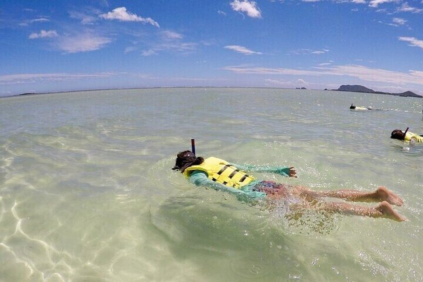 A person floating on a yellow and blue inflatable in clear turquoise water with a distant landmass. 5