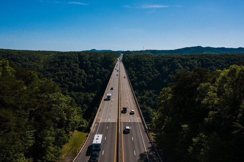 A highway with vehicles, surrounded by dense forest. 2
